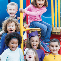 Foto de un grupo diverso de siete niños de primaria en el patio de la escuela.
